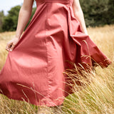 Person wearing a pink dress standing in a field of tall grass.
