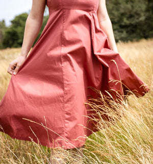 Person wearing a pink dress standing in a field of tall grass.