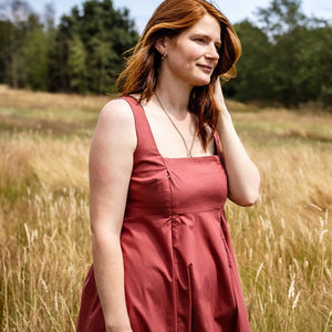 Woman in a red dress standing in a field with trees in the background