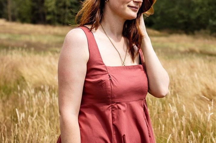Woman in a red dress standing in a field with trees in the background