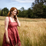 Woman in a red dress standing in a field with trees in the background