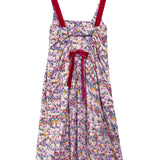 A sleeveless floral midi dress with thin red shoulder straps and a matching red bow at the waist, featuring an all-over multicolor floral print on a light background.