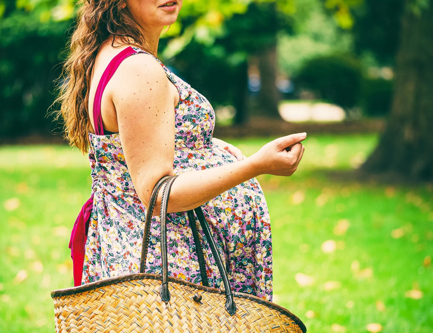 Woman holding a straw bag in a park setting