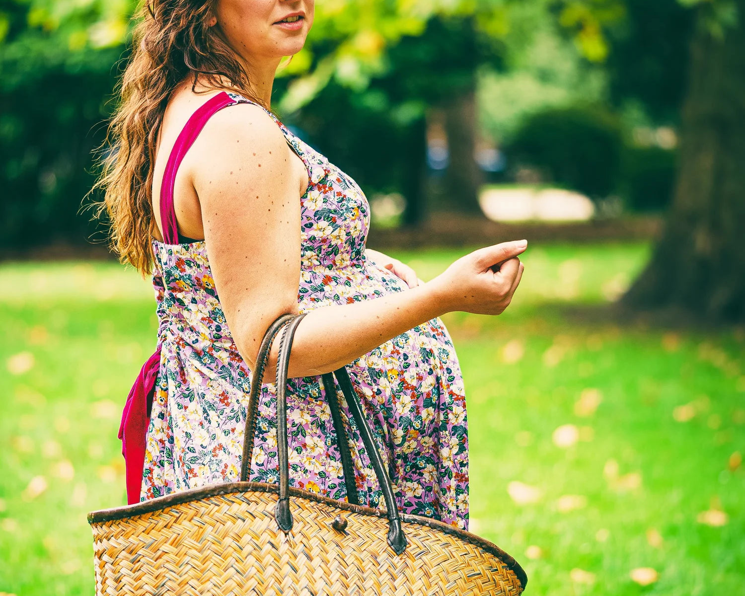 Woman holding a straw bag in a park setting