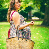 Woman holding a straw bag in a park setting