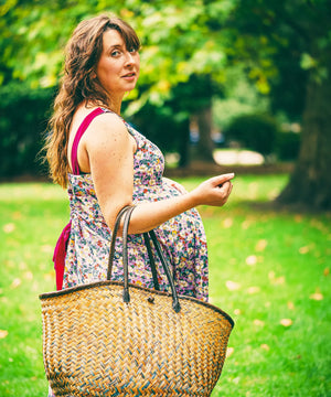 Woman holding a straw bag in a park setting