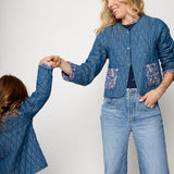 Two people wearing matching blue quilted jackets and jeans on a white background