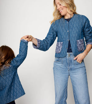 Two people wearing matching blue quilted jackets and jeans on a white background