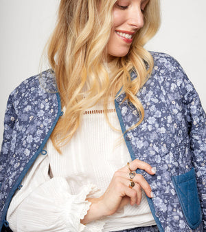 Woman wearing a blue floral jacket over a white top against a plain background
