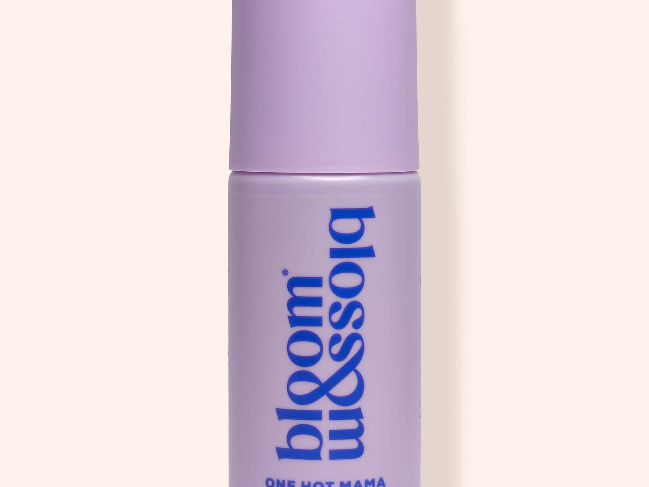 A lavender purple cylindrical bottle of bloom & soho One Hot Mama Revitalising Face & Body Mist, shown against a solid pale peach background.