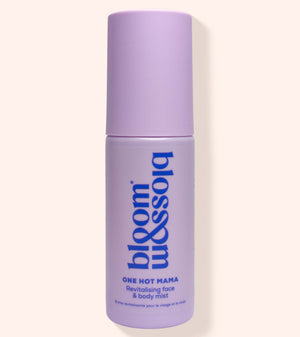 A lavender purple cylindrical bottle of bloom & soho One Hot Mama Revitalising Face & Body Mist, shown against a solid pale peach background.