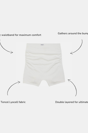 White high-waisted briefs centered on a light gray background with four black arrows and text callouts describing comfort features: folded fabric waistband, gathers around the bump, buttery soft Tencel Lyocell fabric, and double layered construction.