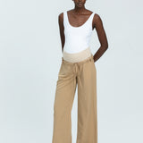 Woman wearing a white tank top and beige wide-leg pants on a white background