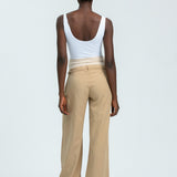 Person wearing a white tank top and beige pants on a light gray background