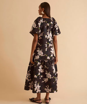 Model wearing floral puff sleeve tiered midi dress in chocolate blossom print.