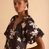 Model wearing floral puff sleeve tiered midi dress in chocolate blossom print.