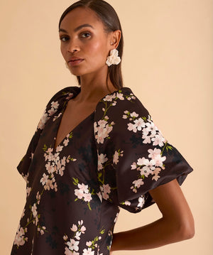 Model wearing floral puff sleeve tiered midi dress in chocolate blossom print.