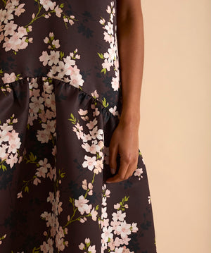 Model wearing floral puff sleeve tiered midi dress in chocolate blossom print.