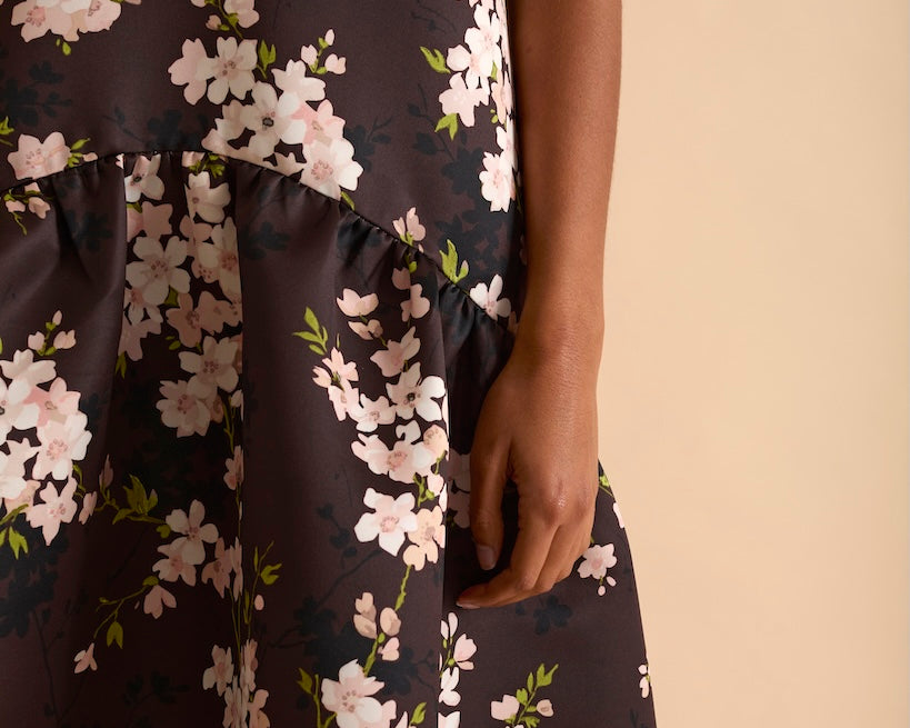 Model wearing floral puff sleeve tiered midi dress in chocolate blossom print.
