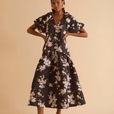 Model wearing floral puff sleeve tiered midi dress in chocolate blossom print.