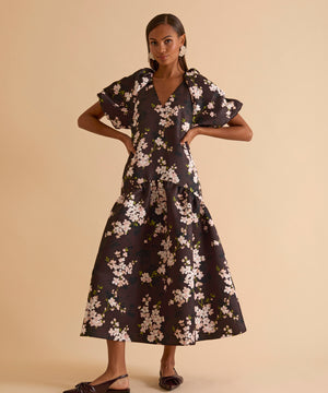 Model wearing floral puff sleeve tiered midi dress in chocolate blossom print.