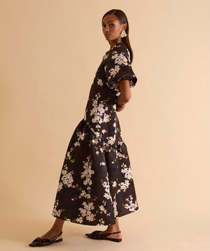 Model wearing floral puff sleeve tiered midi dress in chocolate blossom print.