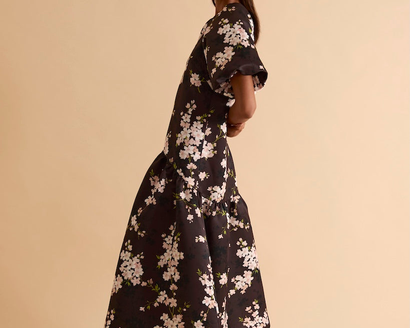 Model wearing floral puff sleeve tiered midi dress in chocolate blossom print.