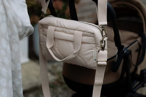 Neutral quilted baby changing bag by Ralphie Bear with waterproof lining, zip compartments, and adjustable strap.