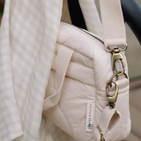 Neutral quilted baby changing bag by Ralphie Bear with waterproof lining, zip compartments, and adjustable strap.