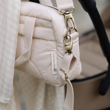 Neutral quilted baby changing bag by Ralphie Bear with waterproof lining, zip compartments, and adjustable strap.