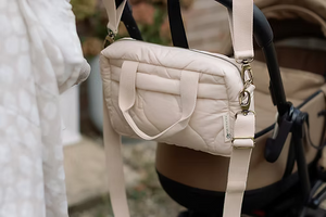 Neutral quilted baby changing bag by Ralphie Bear with waterproof lining, zip compartments, and adjustable strap.