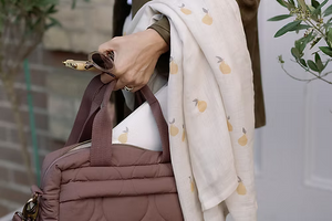 Neutral quilted baby changing bag by Ralphie Bear with waterproof lining, zip compartments, and adjustable strap.