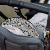 Gray diaper bag with floral lining attached to a stroller