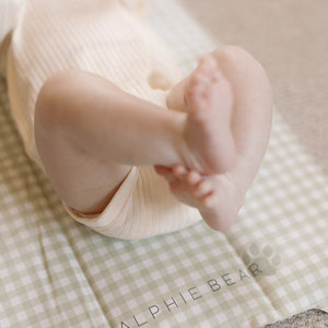 Baby lying on a green checkered blanket with 'RALPHIE BEAR' branding.