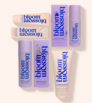 A set of seven Bloom & Assoi skincare products arranged on a light cream background. The products include tubes, bottles, and boxes in lavender purple and pale peach-beige colors with bold blue branding.