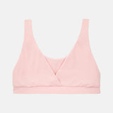 A light pink wireless bralette with a wrap-style crossover neckline and wide shoulder straps, shown flat against a light gray background.