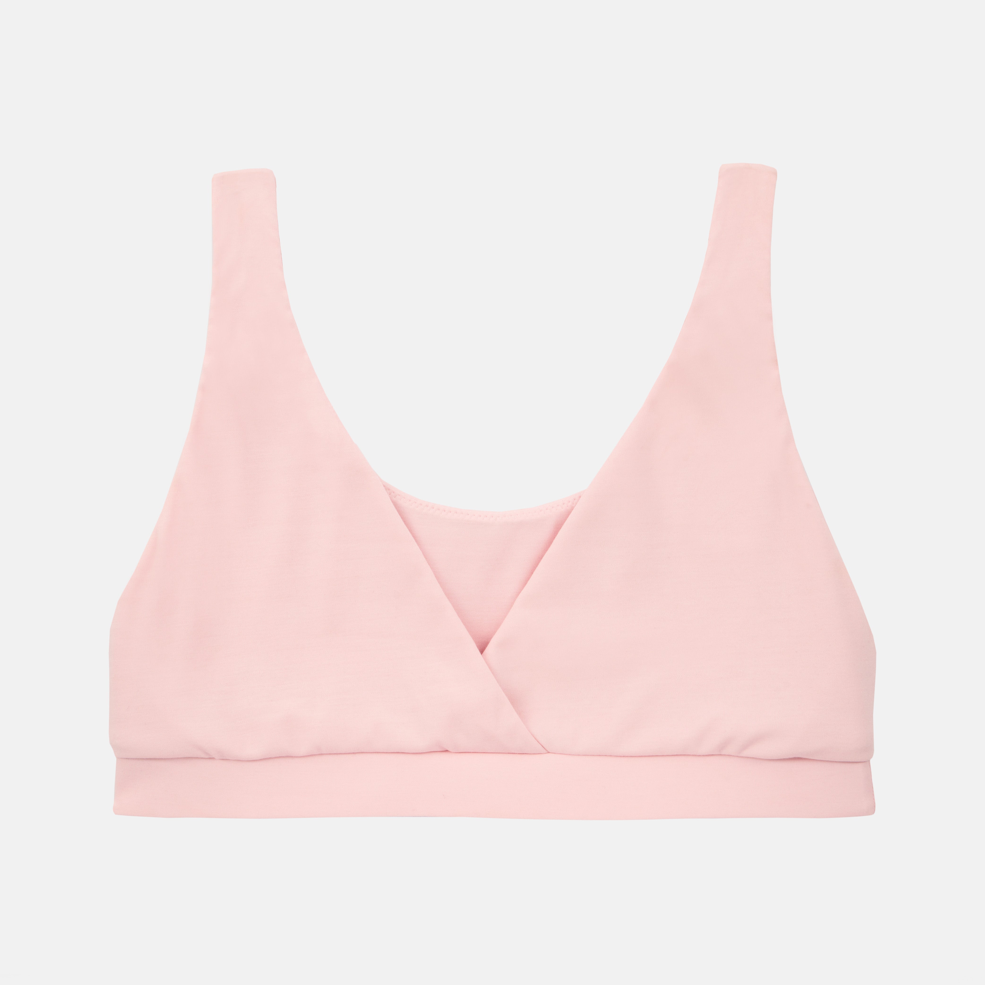 A light pink wireless bralette with a wrap-style crossover neckline and wide shoulder straps, shown flat against a light gray background.