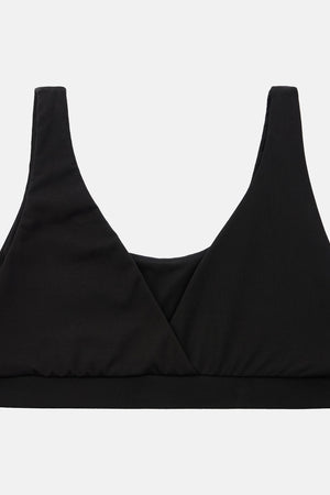 A black wrap-style sports bra or bralette with wide shoulder straps and a wide underband, shown flat against a light gray background.