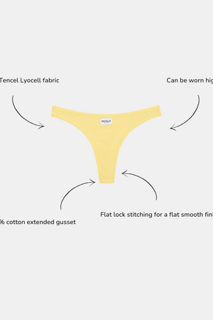 A pale yellow thong-style underwear piece centered on a light gray background, with arrows and text callouts describing its soft Tencel Lyocell fabric, adjustable high or low rise, and flat lock stitching.