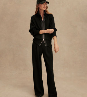 Woman wearing Varley Roxbury zip-through sweatshirt in black DoubleSoft® fabric with high neck and front pockets.