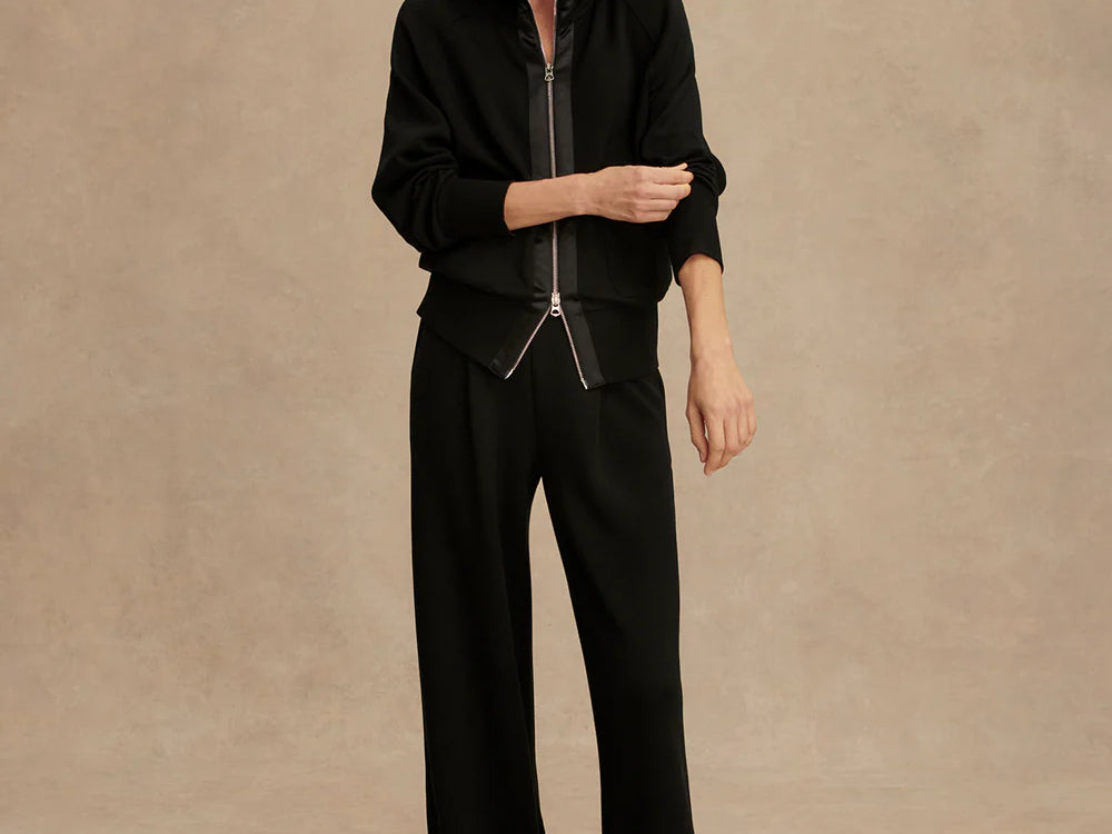 Woman wearing Varley Roxbury zip-through sweatshirt in black DoubleSoft® fabric with high neck and front pockets.