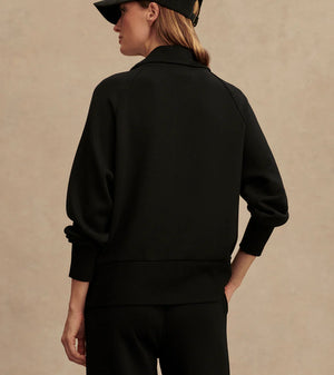 Woman wearing Varley Roxbury zip-through sweatshirt in black DoubleSoft® fabric with high neck and front pockets.