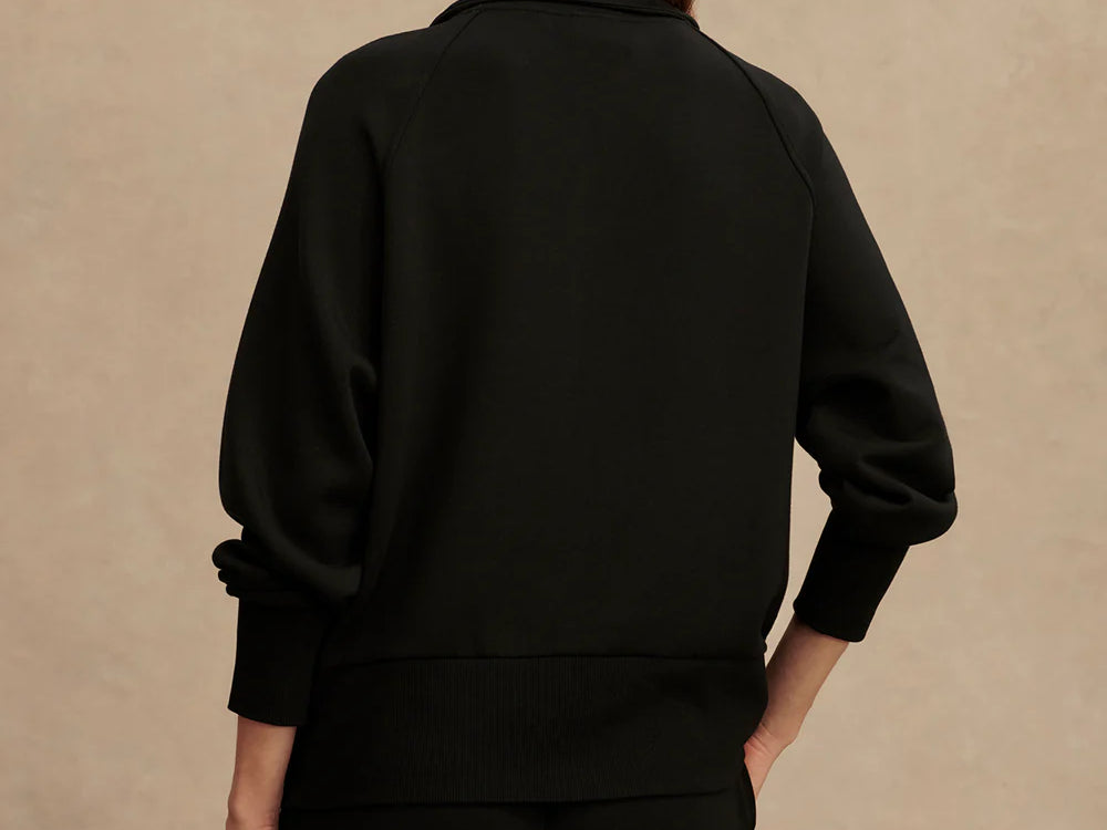 Woman wearing Varley Roxbury zip-through sweatshirt in black DoubleSoft® fabric with high neck and front pockets.