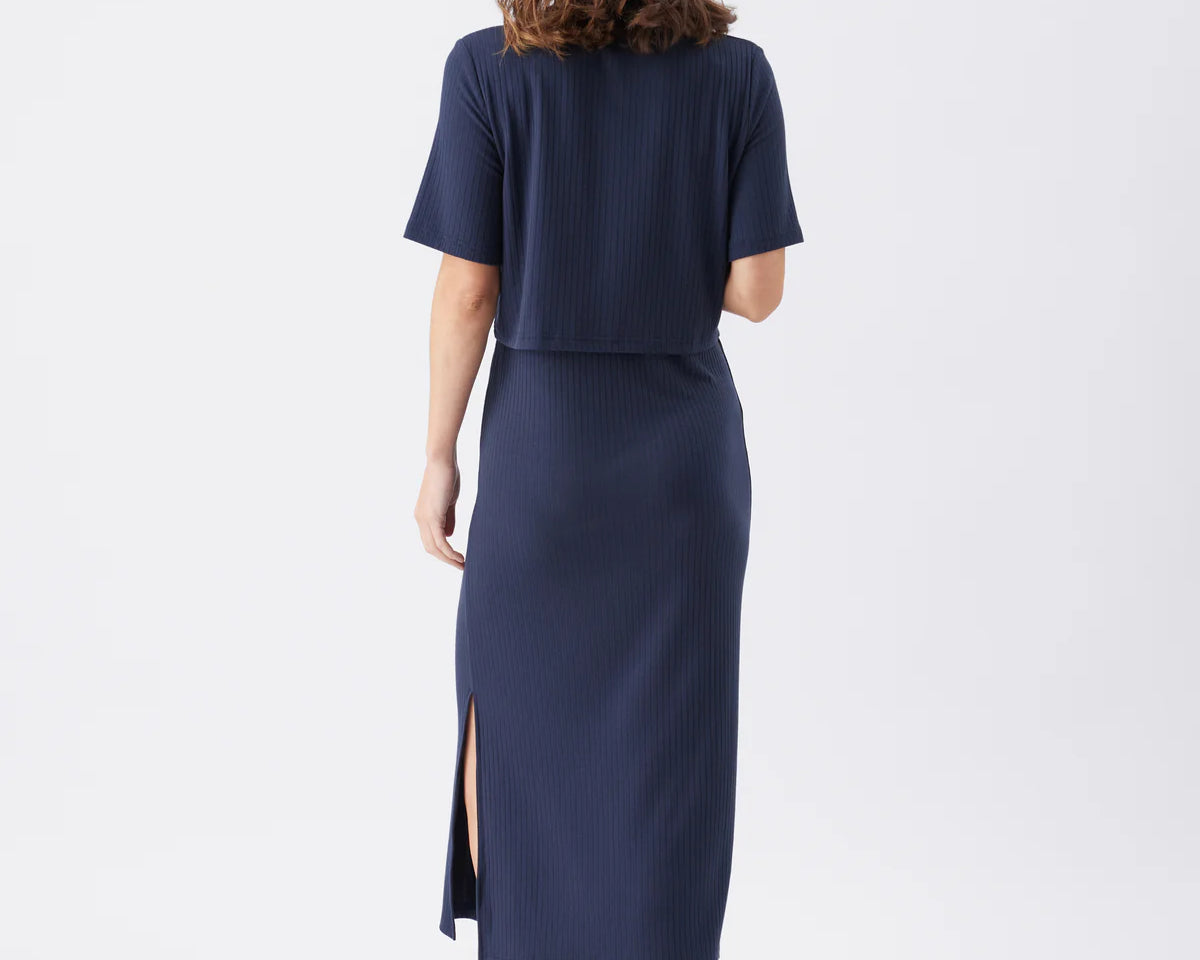 Woman wearing a navy blue outfit with a skirt on a white background