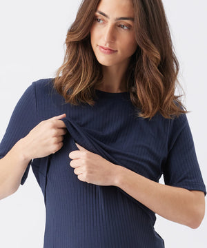 Woman wearing a navy blue ribbed dress against a white background