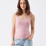 Woman wearing a pink tank top and light blue jeans on a white background