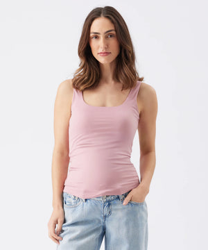 Woman wearing a pink tank top and light blue jeans on a white background