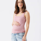 Woman wearing a pink tank top and light blue jeans on a white background