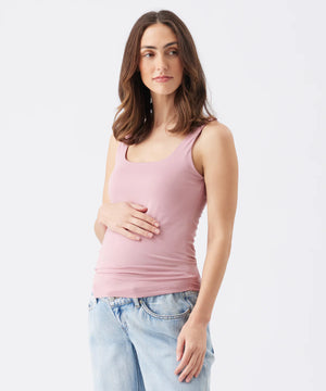 Woman wearing a pink tank top and light blue jeans on a white background