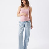 Woman wearing a pink tank top and light blue jeans on a white background